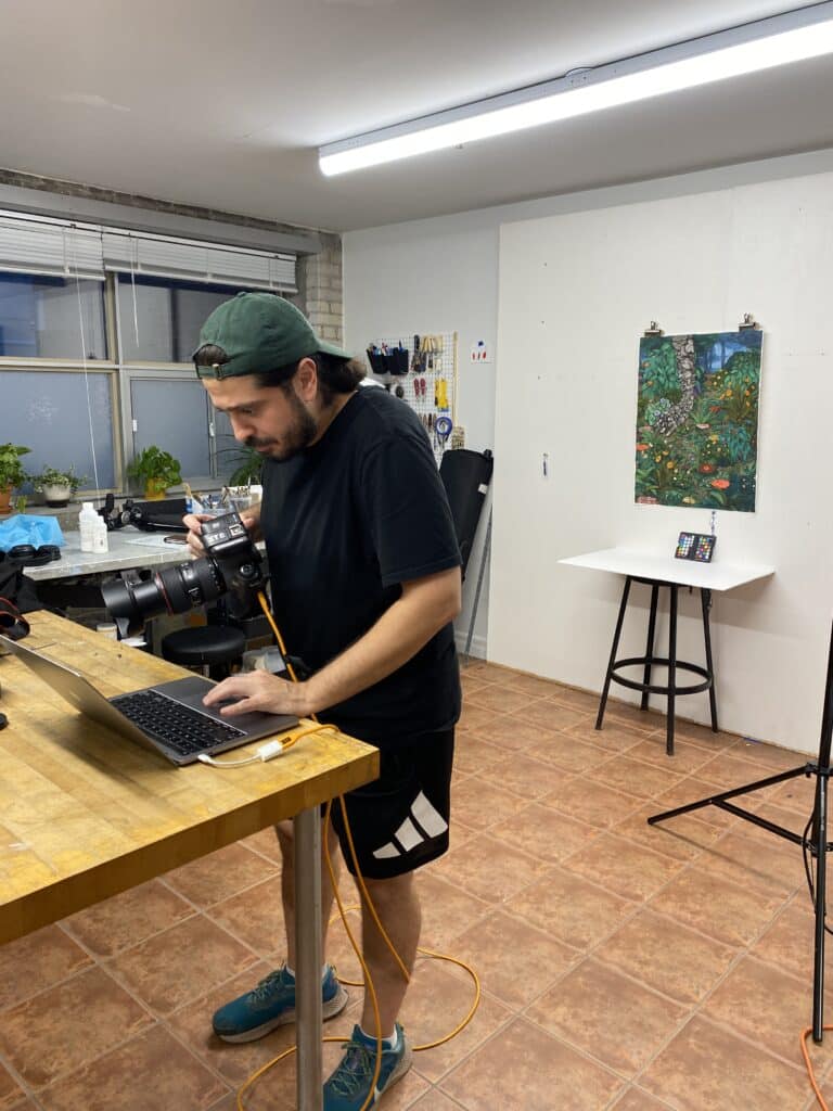 Ibrahim Abusitta checking images on a tethered laptop while documenting artwork by Stanzie Tooth