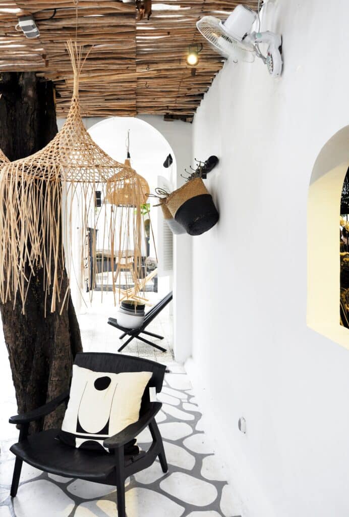 stone floor with organic shaped tiles, modern black chair with white and black throw pillow, and grass chandelier