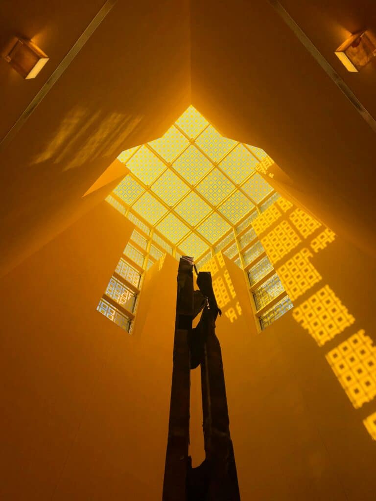 wooden ladder in light filled room with high ceiling and textured skylights making patterns on the walls